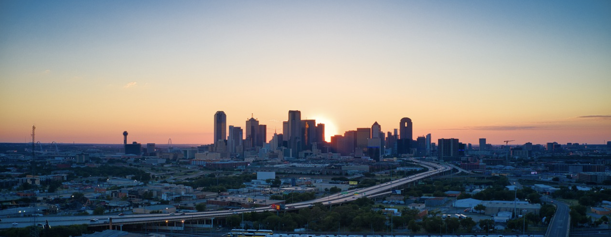 Aerial view of downtown Dallas skyline at sunrise, with highways and buildings shaping the future of this vibrant Mid-America city.