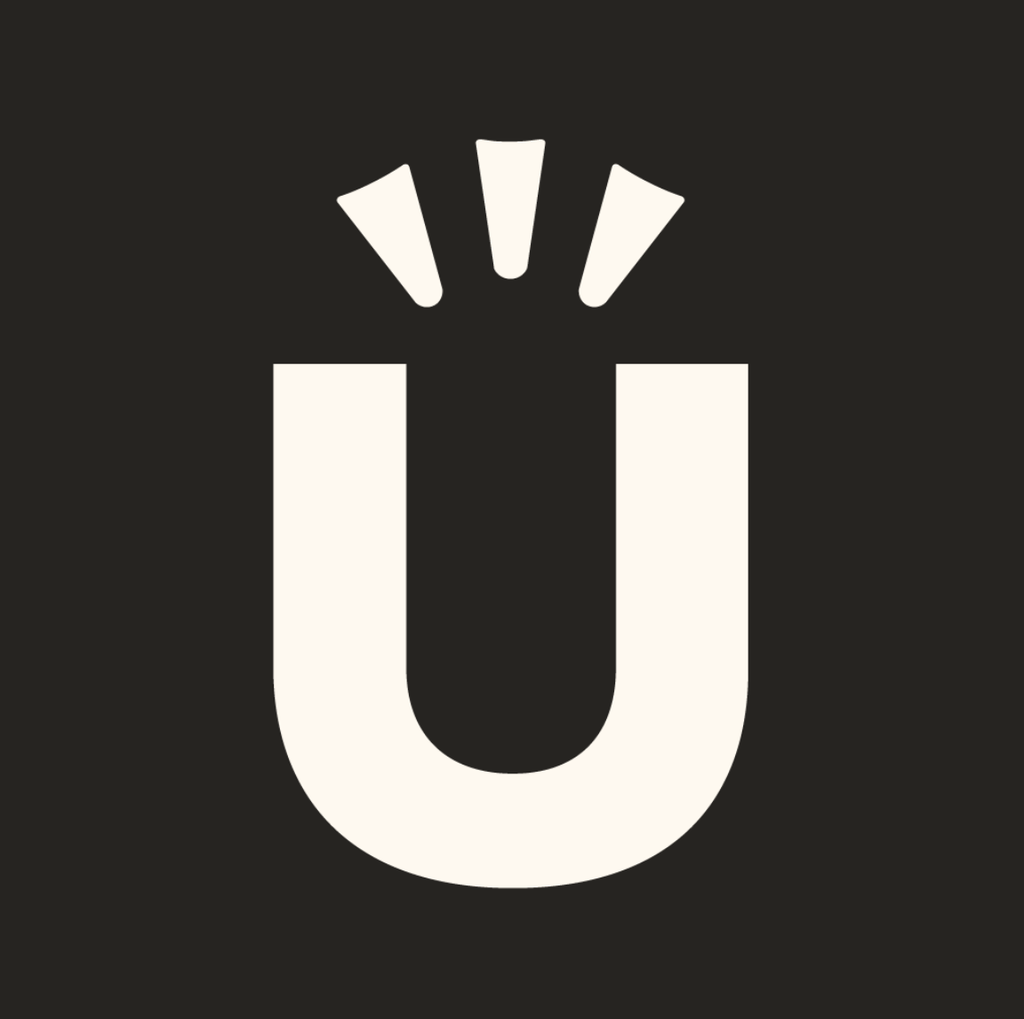 A bold, white capital letter U with three short lines above it on a black background, reminiscent of the distinctive design style seen in Corner Table Creative’s iconic works—suggesting emphasis or attention.