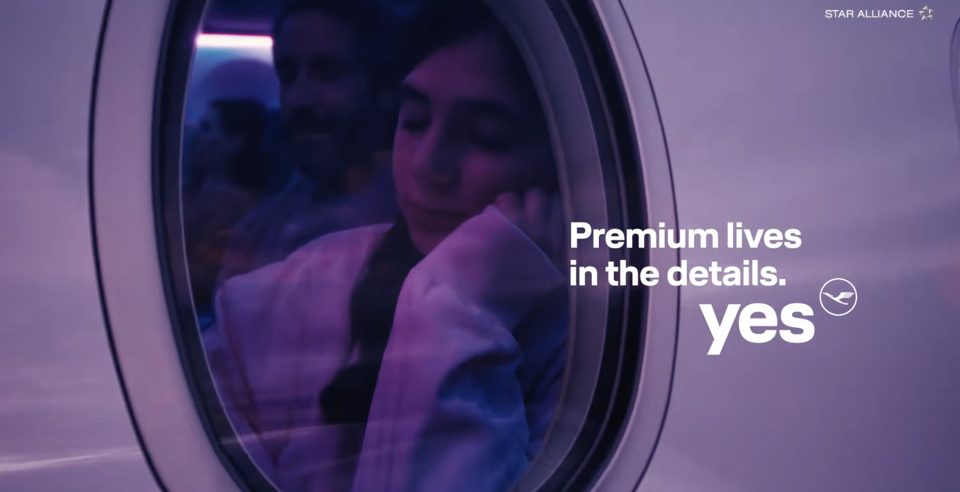 A person rests against an airplane window at dusk. Text on the window reads, Premium lives in the details. yes, with the Lufthansa logo.